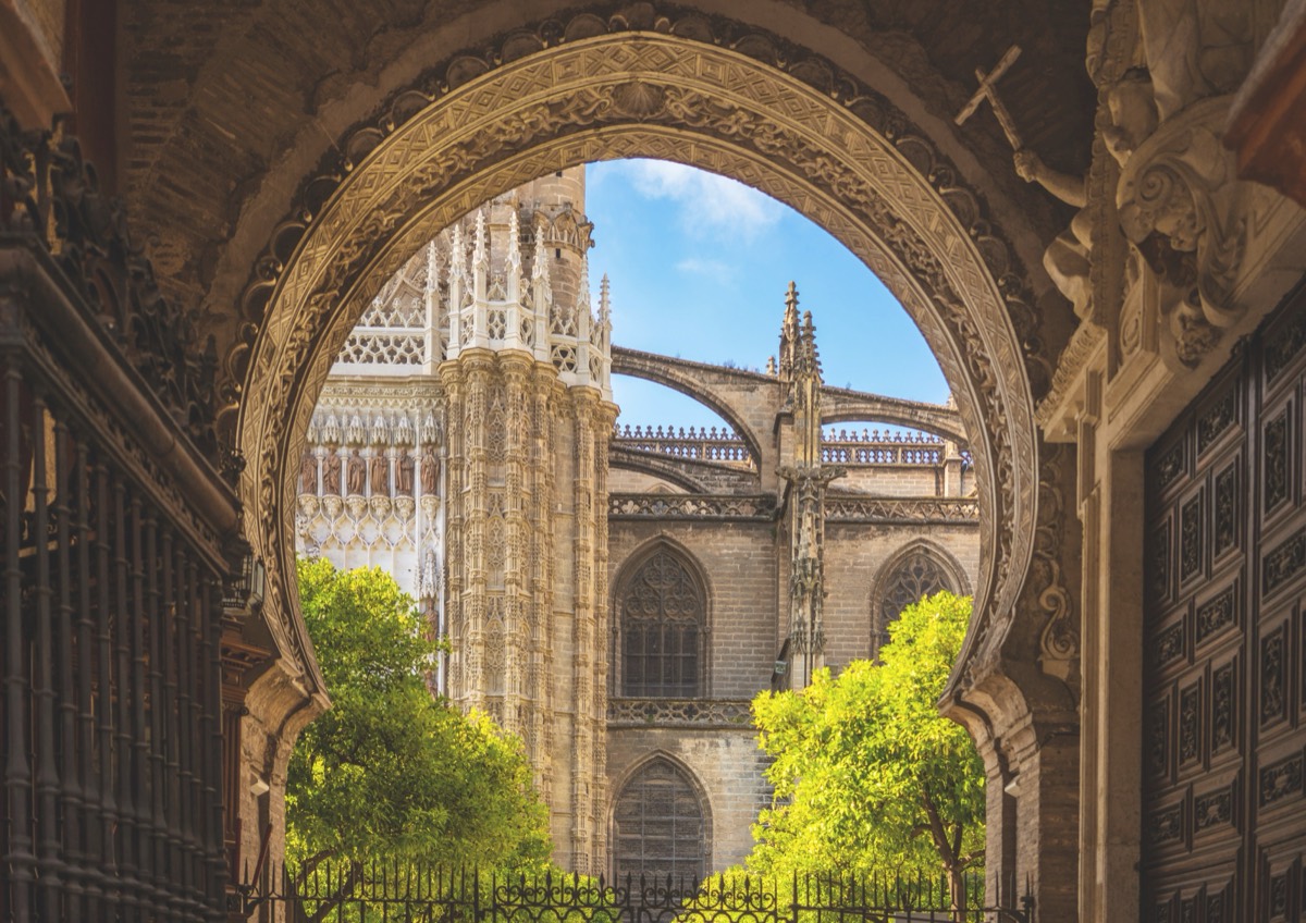 View through a horseshoe arch toward the buttresses and spires of Seville Cathedral